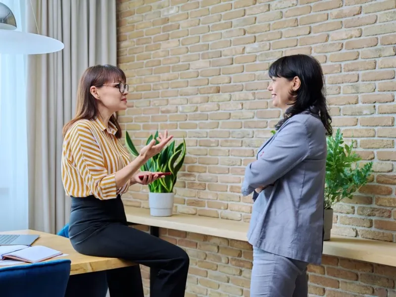 two mature business women are talking in a modern office e1694367459151.jpg